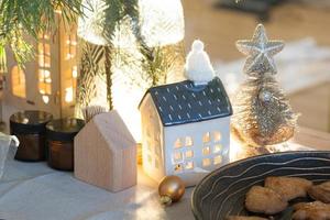 Festive Christmas decor in table, homemade cakes for breakfast, bakery cookies. Cozy home, christmas tree with fairy lights garlands. New Year, christmas mood