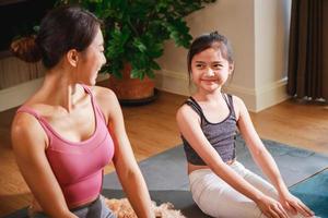 Mom and Little Girl doing exercises by using online learning with a laptop computer at home photo