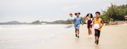 Banner size. Happy Group of African American kids wind turbine toy on the beach photo