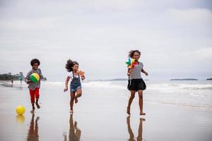 felices tres niños afroamericanos divirtiéndose en una playa tropical. concepto étnicamente diverso foto