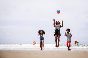 grupo de niños afroamericanos felices saltando en una playa tropical. concepto étnicamente diverso foto