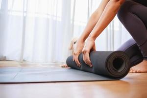 Close-up of woman hands unrolling roll black yoga mat at home, New normal lifestyle concept photo