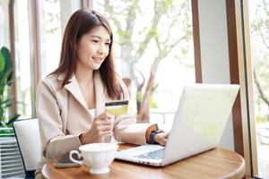 Asian woman use a credit card for goods payments shopping online by laptop. business concept. photo