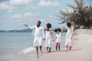 Happy family Mother, Father, Two daughters walking together on the beach on holiday photo