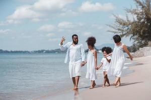 African American family walking together on the beach. Having fun on a tropical beach. photo