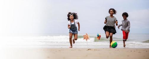 Banner size. Group of Happy African American children running on a tropical beach photo