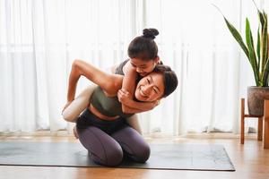 Mom teaching her kid to yoga pose and exercise together on yoga mat in living room at home photo