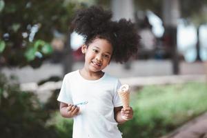 niña comiendo cono de helado en el parque al aire libre foto