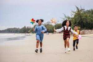 feliz grupo de niños afroamericanos disfrutando de su tiempo en la playa foto