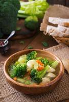 Chicken soup with broccoli, green peas, carrots and celery in  bowl on a wooden background in rustic style photo