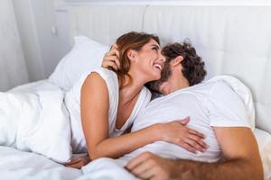 hermosa pareja amorosa besándose en la cama. hermosa joven pareja acostada juntos en la cama. joven pareja romántica enamorada acostada en la cama. hermosa pareja sonriendo en la cama. foto