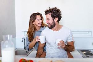 pareja romántica enamorada pasando tiempo juntos en la cocina. linda pareja joven tomando café en la cocina y disfrutando juntos de la mañana foto