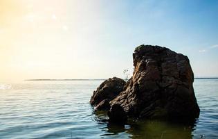 Lonely rocks on the shore of the lake with wind waves.  orange sun shines  gives a feeling of strength, hope photo