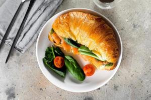 Croissant sandwich with cottage cheese, salmon, spinach. Healthy breakfast. Top view, copy space photo