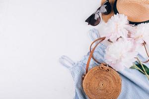 Woman's travel accessories dress, rattan bag, straw hat on white background. Flat lay, top view photo