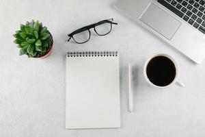 Office desk table with open notebook, cup of coffee and laptop New year 2022 resolutions or goals list. Flat lay, copy space photo