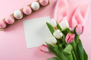 composición plana de Pascua. huevos de pascua, tarjeta vacía en blanco y tulipanes de primavera. concepto de maqueta.