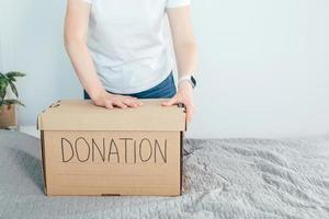 Woman holding donation box with clothes and personal items. Domestic life, lifestyle photo