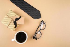 Gift boxes, paper mustacher, eyeglasses, tie, cup of coffee on neutral background. Happy Fathers Day concept. Top view, copy space photo