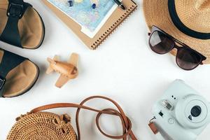 Travel flat lay. Handbag, straw hat, sunglasses, sandals, camera, notebook, map, airplane. Top view photo