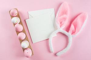 Easter eggs, fluffy bunny ears, white empty card for congratulations. Mockup. Easter holiday concept photo