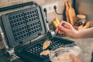 Young woman preparing Belgian waffles in the kitchen. Cooking process photo