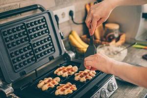 Young woman preparing Belgian waffles in the kitchen. Cooking process photo