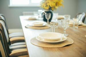 Wooden table with empty plates and glasses. Festive Easter table setting. Branches of mimosa in vase photo