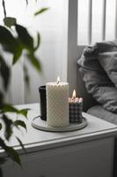 Luxury aroma burning candle in bedroom on bedsite table. Home cozy interior photo