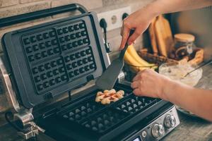 Young woman preparing Belgian waffles in the kitchen. Cooking process photo