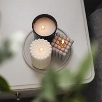 Modern burning candle on bedside table near bed. Home aroma. Wellness. photo