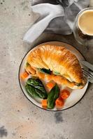 Croissant sandwich with cottage cheese, salmon, spinach, glass of coffee. Healthy breakfast photo