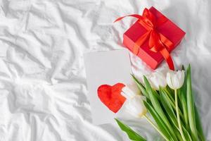 flores de tulipanes, caja de regalo roja y tarjeta vacía con corazón para texto. Bosquejo. concepto del día de la mujer, día de la madre.