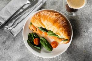 Croissant sandwich with cottage cheese, salmon, spinach. Healthy breakfast. Top view, copy space photo