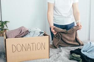 caja de donación con ropa. mujer preparando ropa para donación foto