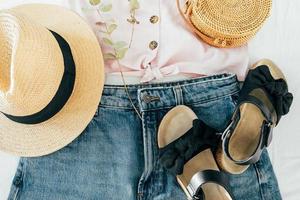 Beauty blog concept. Summer female clothes, accessories. Sandals, denim shirt, top, hat, rattan bag photo