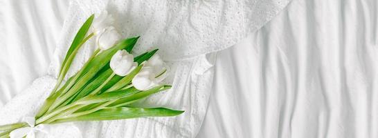 White tulips flowers on white textile background. Easter, Spring holiday concept. Long panoramic banner for design. photo