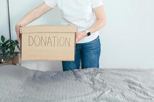 Woman holding donation box with clothes and personal items. Domestic life, lifestyle photo