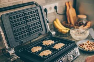 Young woman preparing Belgian waffles in the kitchen. Cooking process photo