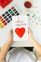 Happy mothers day card made by a child. Girl drawing card for mom for the holiday with watercolors. photo