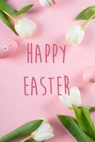Happy Easter text on greeting card. Easter holiday concept. Tulips and easter eggs. Flat lay, top view photo