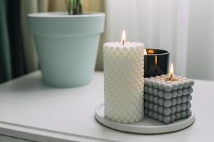 Burning bubble candle on bedsite table in bedroom. Trendy home decor. photo