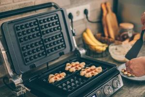 Young woman preparing Belgian waffles in the kitchen. Cooking process photo