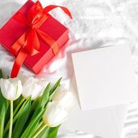 flores de tulipanes, caja de regalo roja y tarjeta vacía para texto. Bosquejo. concepto del día de la mujer, día de la madre foto