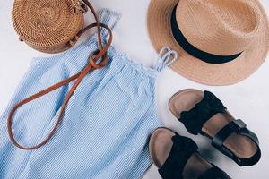 Women's fashion flat lay. Stylish female clothes - straw hat, blue dress, rattan bag, sandals. photo