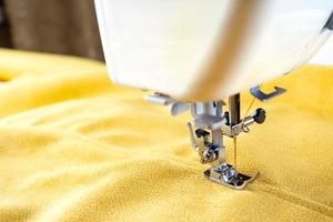 máquina de coser moderna y tela amarilla. proceso de costura, hecho a mano, hobby, bricolaje, negocio, reparación foto