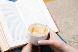 cup of coffee and a book in female hand photo