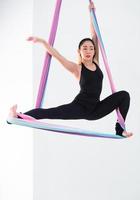 Young beautiful Asian dancer dressed in black color performing aerial dance with multi-color fabrics in the studio. photo