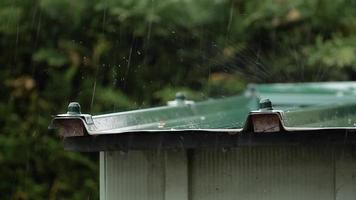 Pouring rain on the roof of the garden shed. In slow motion video