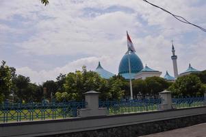 vista de la gran mezquita con la cúpula y la bandera indonesia delante. foto